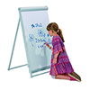 Kind zeichnet mit blauer Farbe auf einer Flipchart-Tafel, die auf niedriger Höhe steht.
