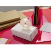 Transparenter Klebefilm auf einem weißen Karton neben weiteren Büromaterialien.