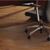 Durchsichtige Bodenschutzmatte unter einem Bürostuhl auf einem Holzboden.