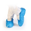 Blaue Überschuhe aus Kunststoff über weißen Straßenschuhen in einer stehenden Position.