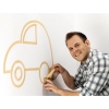 Mann klebt Kreppband an Wand zur Gestaltung eines Auto-Motivs.