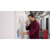 Mann verwendet Klebstoffentferner-Spray und wischt mit einem Tuch an einer Wand.