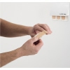 Person verwendet ein Pflaster aus einem weißen Pflasterspender an der Wand.