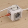 Steckdosenwürfel mit vier Steckdosen und zwei USB-Ladebuchsen auf einem Holztisch.