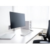Monitorarm montiert an einem Schreibtisch mit einem Bildschirm, Laptop und Tastatur.