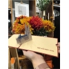 Drei-dimensional gefaltete Klappkarte mit Miniatur des Kölner Doms vor buntem Blumenarrangement.