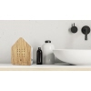 Holz-Lautsprecher in Hausform steht auf einem Regal neben Flasche und Schüssel.