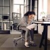 Bodenschutzmatte unter einem Bürostuhl in einem modernen Büro mit arbeitender Person.