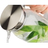 Karaffe mit Edelstahlverschluss, die Wasser mit Minze ausgießt.