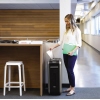 Eine Person nutzt einen Aktenvernichter neben einem Schreibtisch in einem modernen Büro.
