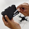Hand, die eine AAA-Batterie in ein Gerät einsetzt, im Hintergrund ein Spielzeug-Drone.