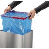 Person installiert eine blaue Mülltüte in einen Edelstahl-Abfalleimer mit einem Klemmrahmen.