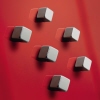 Sechs quadratische Magnetwürfel haften an einem roten Glas-Magnetboard.