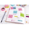 Bunte Haftnotizwürfel in verschiedenen Farben auf einem Planer mit Stift und Klebeband.