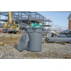 Grauer Rubbermaid Abfalleimer BRUTE® 121 l mit Inhalt auf einer Baustelle in urbaner Umgebung.