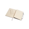 Offenes schwarzes Moleskine Notizbuch mit anliegendem Informationsblatt in neutralem Umfeld.