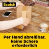 Person beklebt einen Karton mit selbstklebendem Packband auf einem Tisch.
