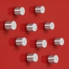 Zehn silberne Zylinder-Magnete auf einer roten Wandoberfläche.