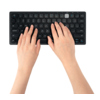 Zwei Hände tippen auf einer kompakten, kabellosen Tastatur.