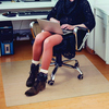 Bodenschutzmatte unter einem Bürostuhl, mit einer Person, die an einem Laptop arbeitet.