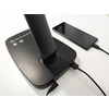 Schreibtischlampe mit touchsensitiven Bedienelementen und Smartphone zum Laden auf einem Tisch.