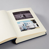 Offenes Fotoalbum mit zwei eingelegten Fotos auf beigem Innenseitenpapier.