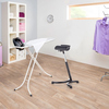 Schwarzer Stehhocker mit ergonomischer Sitzfläche steht neben einem Bügelbrett in einem Raum.