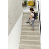 Frau mit Rucksacksauger reinigt eine Treppe in einem modernen Raum.