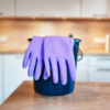 Lila Gummihandschuhe liegen auf einem Eimer in einer modernen Küchenumgebung.