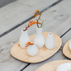 Vier kleine weiße Vasen mit Blumen auf einem Holztablett.