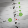 Leuchtgrüne Markierungspunkte auf einem Kalenderblatt zur Organisation von Terminen.