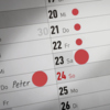 Rote Markierungspunkte auf einem Kalender zur Kennzeichnung von Terminen.