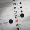 Schwarze Markierungspunkte auf einem Kalenderblatt zur Kennzeichnung von Terminen.