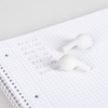 Weißer Radierer in Form von In-Ear-Pods liegt auf kariertem Notizblock mit Zahlen.
