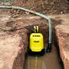 Wasserschlauch neben einer Pumpe in einer mit Wasser gefüllten Grube.