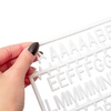 Eine Hand hält ein Set weißer Kunststoffbuchstaben für ein schwarzes Letterboard.