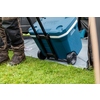 Kühlbox mit Rollen auf Gras, Person zieht sie mit einem Teleskopgriff.