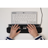 Zwei Hände bedienen eine zentrale ergonomische Maus mit Handgelenkstütze und einer Tastatur.