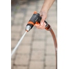 Hand hält eine GARDENA Gartenbrause, die einen feinen Wasserstrahl ausstößt.