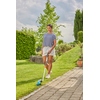 Frau schneidet mit einer akkubetriebenen Grasschere Rasenkanten in einem Garten.