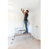 Eine Person steht auf einer MUNK Arbeitsplattform und montiert etwas an der Decke in einem Raum.