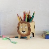 Holz-Stifteköcher in Form eines Löwen mit bunten Stiften im Inneren auf einem Schreibtisch.