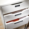 Schubladen mit schwarzen Beschriftungen "Files", "Invoices" und "Office Supplies" auf weißem Möbel.