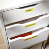 Gelbe Etiketten auf Schubladen mit Beschriftungen zu Inhalten wie Dateien und Büromaterialien.