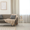 Sitzhocker im Skandi-Stil steht als Ablage neben einem Sofa in einer hellen, modernen Einrichtung.