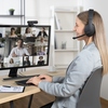 Person mit Over-Ear-Headset sitzt an einem Schreibtisch während eines Videokonferenz-Meetings.