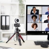Webcam auf einem Stativ neben einem Monitor mit Videoanrufen von mehreren Personen.