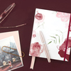 Kugelschreiber in Aluminium rose moon auf einem Notizbuch mit floralen Motiven und Brille.