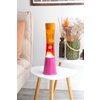 Lavalampe in pink und orange auf einem Tisch neben einem Sofa und dekorativen Elementen.