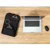 Rucksack mit abnehmbaren Tech-Organizer auf einem Tisch neben einem Laptop und Zubehör.